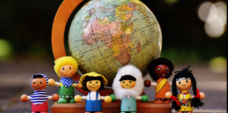 Des figurines montrant des enfants devant une planisphère