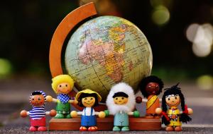 Des figurines montrant des enfants devant une planisphère