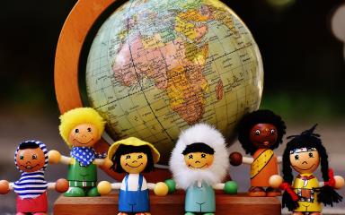 Des figurines montrant des enfants devant une planisphère